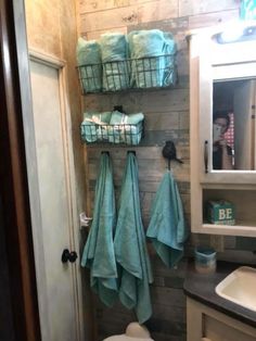 a bathroom with towels hanging on the wall next to a toilet and sink in it