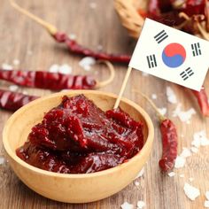 a wooden bowl filled with red food next to other foods on top of a table