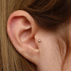 a woman's ear is shown with a single diamond in the middle of it