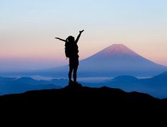 a person standing on top of a mountain with their arms in the air