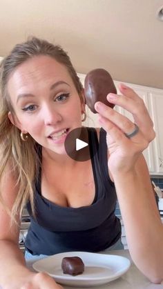 a woman sitting at a table with chocolate covered doughnuts