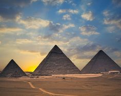 three pyramids in the desert at sunset