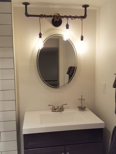 a bathroom with a sink, mirror and lights on the wall above it's faucet