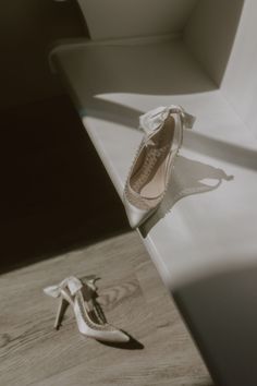 a pair of white shoes sitting on top of a wooden floor next to a window