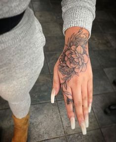 a woman's hand with a flower tattoo on her left wrist and right hand