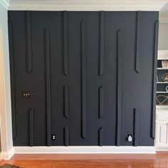 an empty room with black painted walls and wooden floors