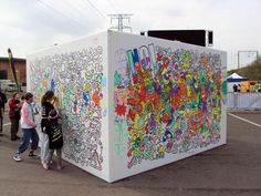 children standing in front of a large white box with graffiti on it's side