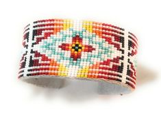 a beaded bracelet with multicolored designs on it's sides and a white background