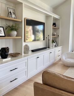 a living room with white cabinets and shelves