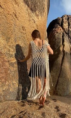 a woman standing next to a large rock