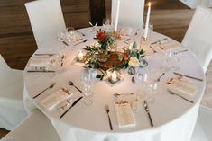 the table is set with white linens and place settings for guests to sit at