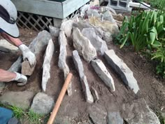 a man is working on some rocks in the yard with an arrow pointing to it