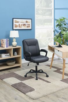 a black office chair sitting on top of a rug in front of a blue wall