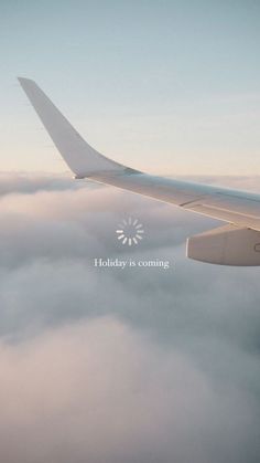 an airplane flying above the clouds with a holiday is coming message on it's side