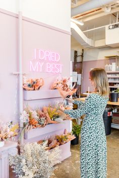 a woman in a floral dress is looking at the shelves with flowers on them and writing i dried my best