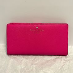 a pink michael kohl wallet sitting on top of a white table next to a wall