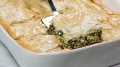 a casserole dish with broccoli and cheese being lifted by a fork