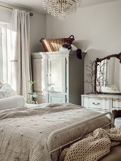 a bedroom with white furniture and a chandelier hanging from the ceiling above it