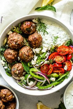 a white bowl filled with meatballs and vegetables