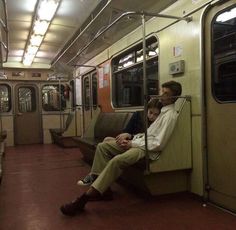 two people are sitting on a subway car