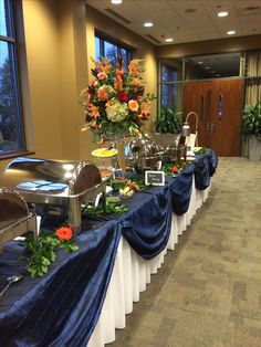 the buffet table is set up with blue cloths and flowers in vases on each side