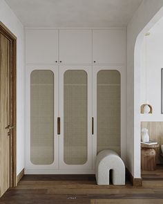 a room with white walls and wooden flooring next to a large cabinet in the corner