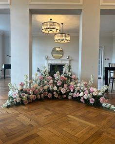 flowers are arranged on the floor in front of a fire place and chandelier