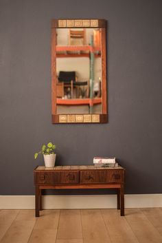 a wooden table with a potted plant on it in front of a wall mirror