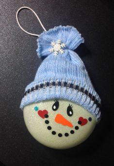 a snowman ornament with a blue hat and scarf on it's head