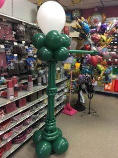 an inflatable balloon is on top of a green lamppost at a store