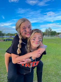 two girls hugging each other in the middle of a field