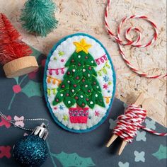 an embroidered christmas ornament next to other ornaments