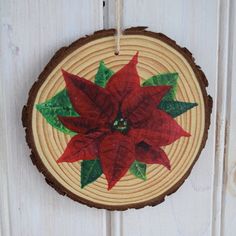 a christmas ornament hanging on a door with red poinsettia leaves