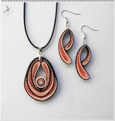 a necklace and earring made out of wood with swirls on the sides, hanging from a black cord