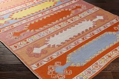 an orange and blue rug on the floor with wood floors in the background at home