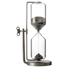 an hourglass with sand in it sitting on top of a metal stand next to a bottle opener