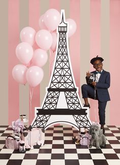 a man in a suit and tie sitting next to a model of the eiffel tower