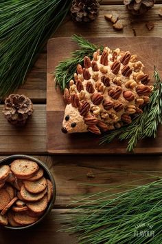 a hedge cookie sitting on top of a wooden cutting board next to pine cones and nuts