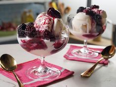 two dessert dishes with ice cream, berries and whipped cream in them on a pink placemat