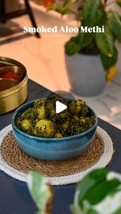 a bowl filled with food sitting on top of a table next to a potted plant