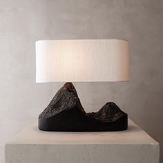 a table lamp sitting on top of a cement block next to a white light shade