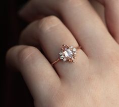 a woman's hand holding an engagement ring with two diamonds on top of it