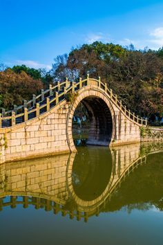 a stone bridge over water with trees in the background