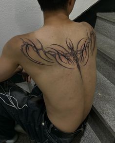 a man is sitting on the stairs with his back tattoo