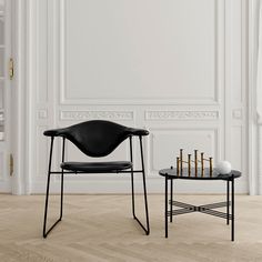 a black chair sitting next to a small table on top of a hard wood floor