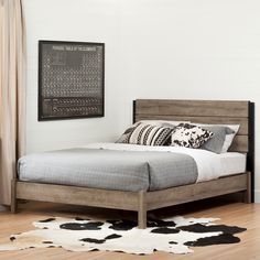 a bed sitting on top of a hard wood floor next to a wall mounted poster