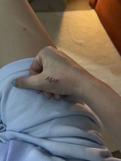 a person with a small tattoo on their left hand and the word asap written in black ink