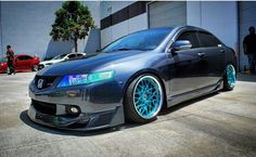 a gray car with blue rims parked in front of a building