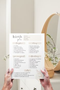 a person holding up a birth checklist in front of a mirror with flowers on it