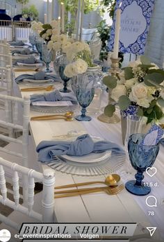 the table is set with blue and white dishes, silverware, and vases